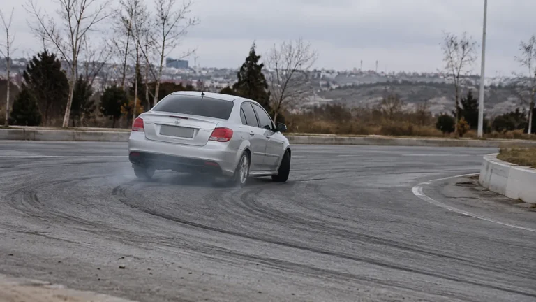 Asfalt üzerinde lastik izi bırakarak drift yapan gri otomobil