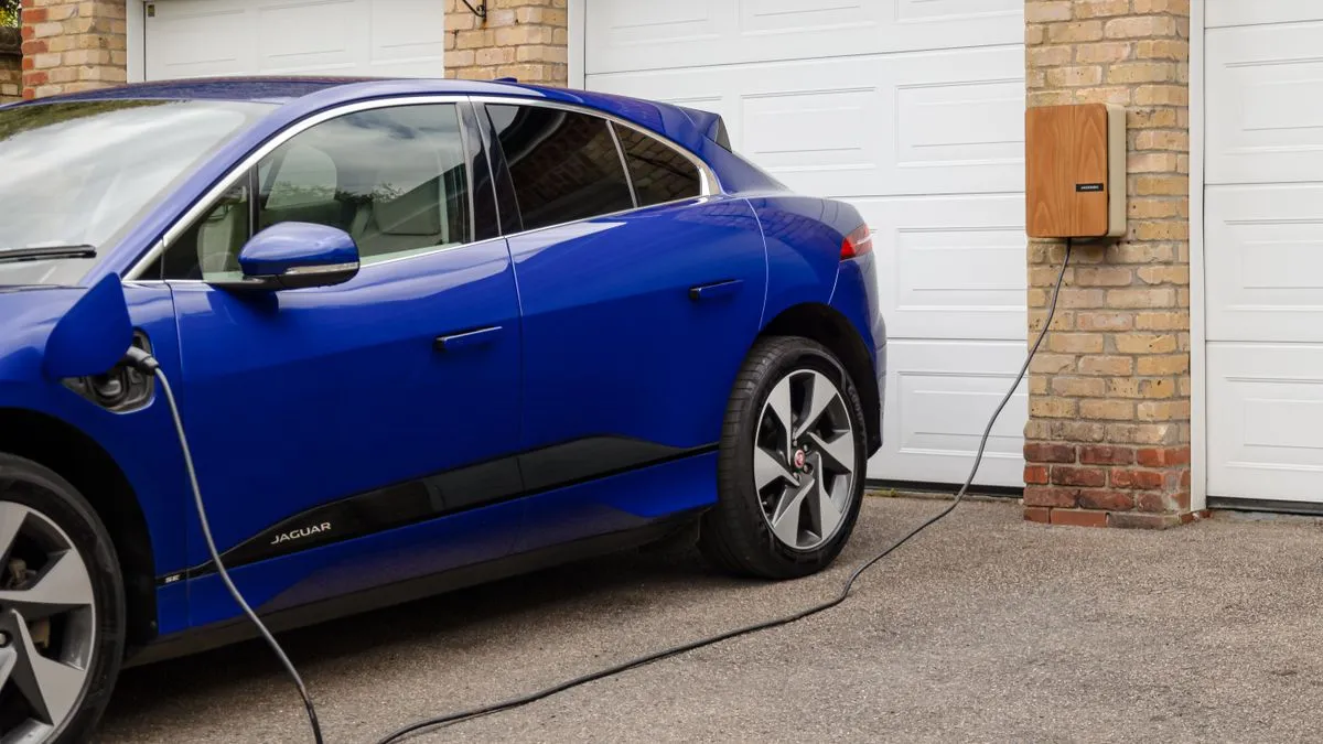 Evin garajında duvara monte şarj ünitesine bağlı elektrikli araç, ev tipi wallbox sigorta kontrolü için temsili fotoğraf