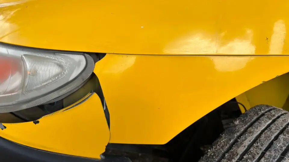 Sarı bir otomobilin darbe ve çizik bulunan ön tamponu ile farı; park yerinde çarpıp kaçma ve Güvence Hesabı konulu rehber için temsili gerçek araç hasarı fotoğrafı