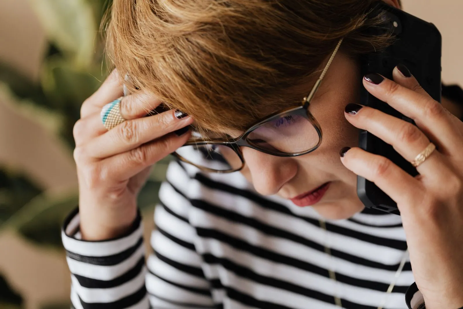 Ofiste telefon görüşmesi sırasında endişeli görünen gözlüklü kadın; ses taklidi dolandırıcılığında şüpheli aramaların doğrulanması rehberini temsil eden gerçek fotoğraf