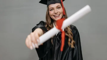 Üniversite mezuniyet kıyafetiyle diplomasını tutan genç; YÖK e-Devlet mezuniyet belgesi alma ve doğrulama rehberi için temsili fotoğraf