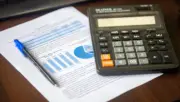 Finansal tabloların ve hesap makinesinin bulunduğu masa üzerinde sigorta sektörünün teknik karlılık değerlendirmesini temsil eden fotoğraf