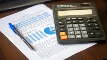 Finansal tabloların ve hesap makinesinin bulunduğu masa üzerinde sigorta sektörünün teknik karlılık değerlendirmesini temsil eden fotoğraf