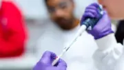 Laboratuvarda pipetle örnek çalışan araştırmacı, genetik testler ve hayat sigortası düzenlemesini temsil eden fotoğraf