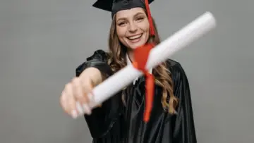Üniversite mezuniyet kıyafetiyle diplomasını tutan genç; YÖK e-Devlet mezuniyet belgesi alma ve doğrulama rehberi için temsili fotoğraf