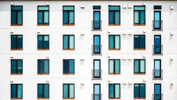 Gün ışığında beyaz cepheli modern apartman binası; binalarda enerji kimlik belgesi ve enerji performansı sınıfı rehberinin temsili görseli