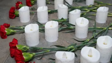 Anma töreninde yere özenle yerleştirilmiş kırmızı karanfiller ve beyaz mumlar; SGK cenaze ödeneği rehberi için saygılı ve temsili fotoğraf