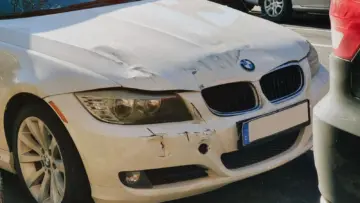Cadde üzerinde ön tamponu hasar görmüş beyaz otomobil; trafik kazasında yüzde 50 kusur oranı ve tazminat rehberi için temsili gerçek fotoğraf