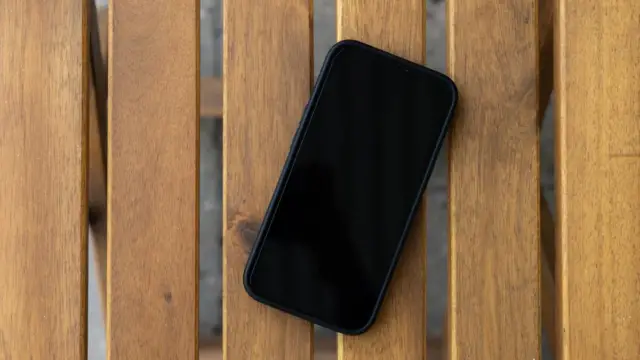 Ahşap masada duran siyah ekranlı akıllı telefon; BTK IMEI kopyalanması ve hat eşleştirme rehberi için temsili gerçek cihaz fotoğrafı