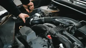 Motor kaputu açık araçta motor ve kabloları inceleyen tamirci; kemirgen nedeniyle kablo hasarının kasko kapsamı için temsili fotoğraf