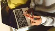 Dizüstü bilgisayarda çevrim içi işlem yaparken kredi kartı tutan kişinin gerçek fotoğrafı; Slingshot Insurance gömülü sigorta altyapısı yatırımı haberi için temsili görsel