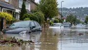İngiltere'de fırtına ve aşırı yağış riskine maruz kalan konut ve araçları temsil eden su basmış yerleşim sokağı
