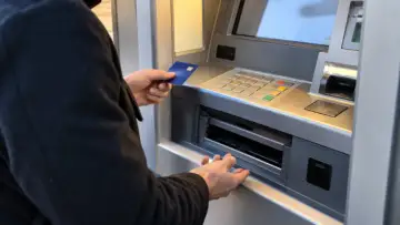 Bankamatik nakit çekme haznesini kontrol eden kişinin doğal görünümlü fotoğrafı; ATM para alıkoyma rehberi