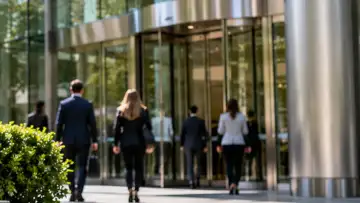 Modern cam cepheli bir iş merkezi girişinde çalışanlar; sigorta brokerliği şirketinin finansal sonuçlarına ilişkin temsili görsel
