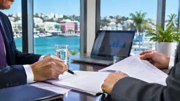 Bermuda manzaralı bir ofiste reasürans portföyü belgelerini inceleyen iş insanları, temsili görsel